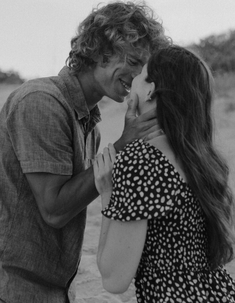 black and white photo of couple kissing on the beach
